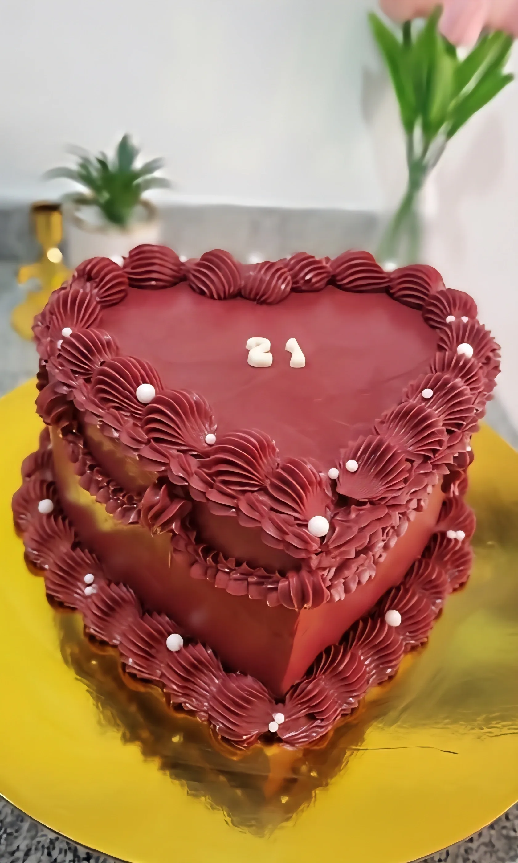 Torta corazón color burdeos con volantes de crema, perlas blancas y número 21.