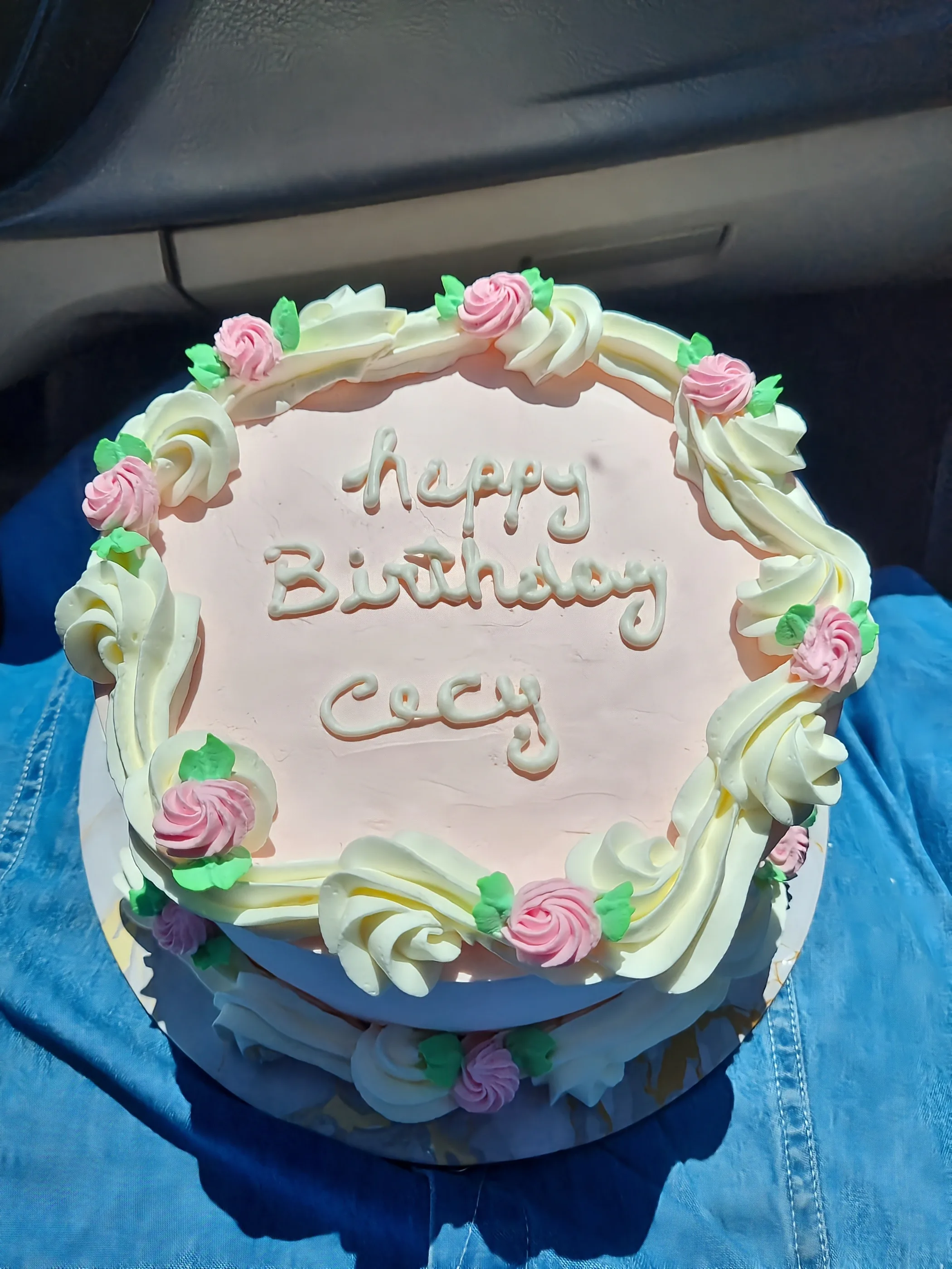 Torta en tonos claros con rosas pequeñas, bordes ondulados y mensaje Happy Birthday Cecy.