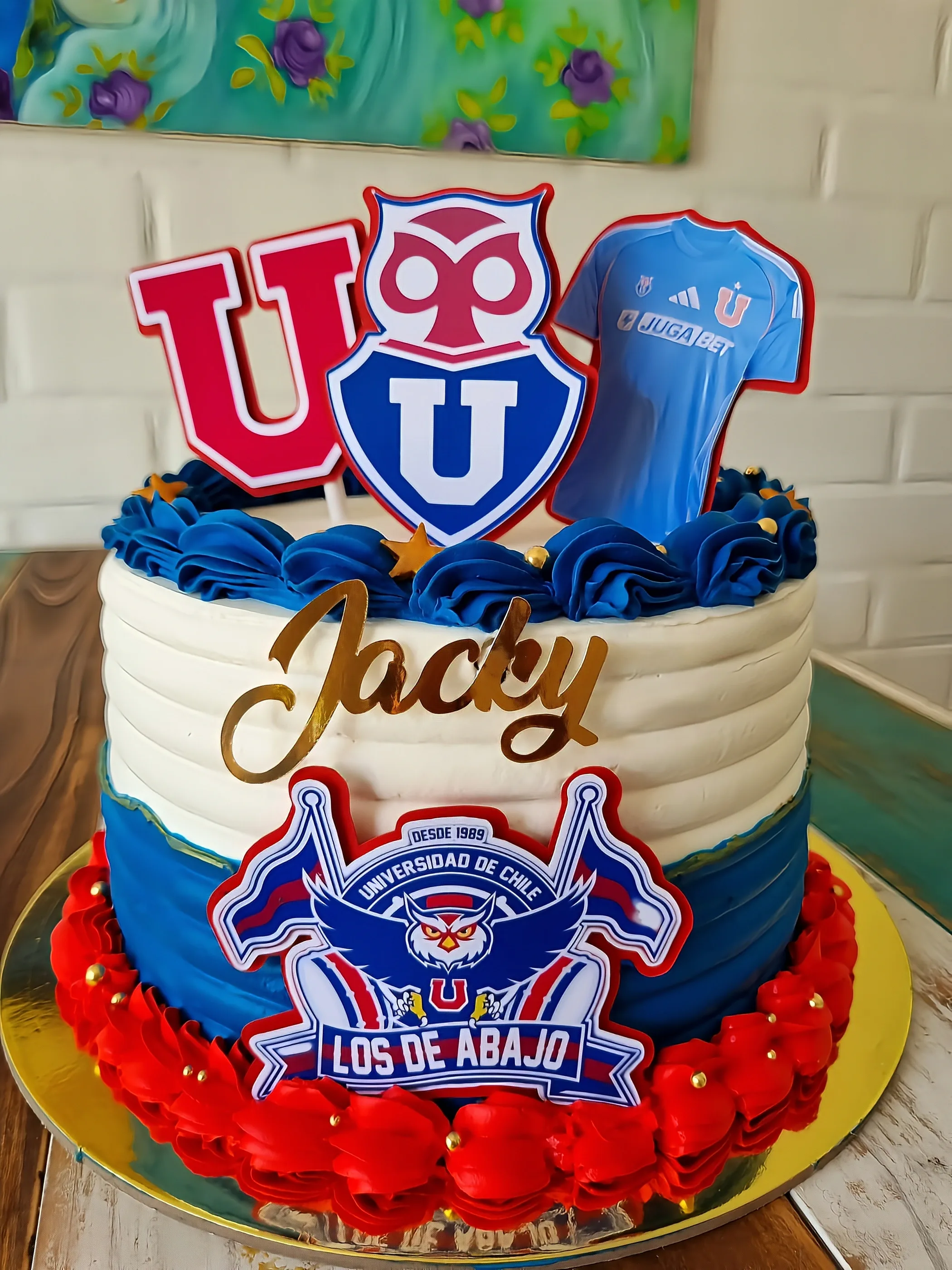 Torta blanca, azul y roja con escudos de Universidad de Chile, camiseta y nombre Jacky.